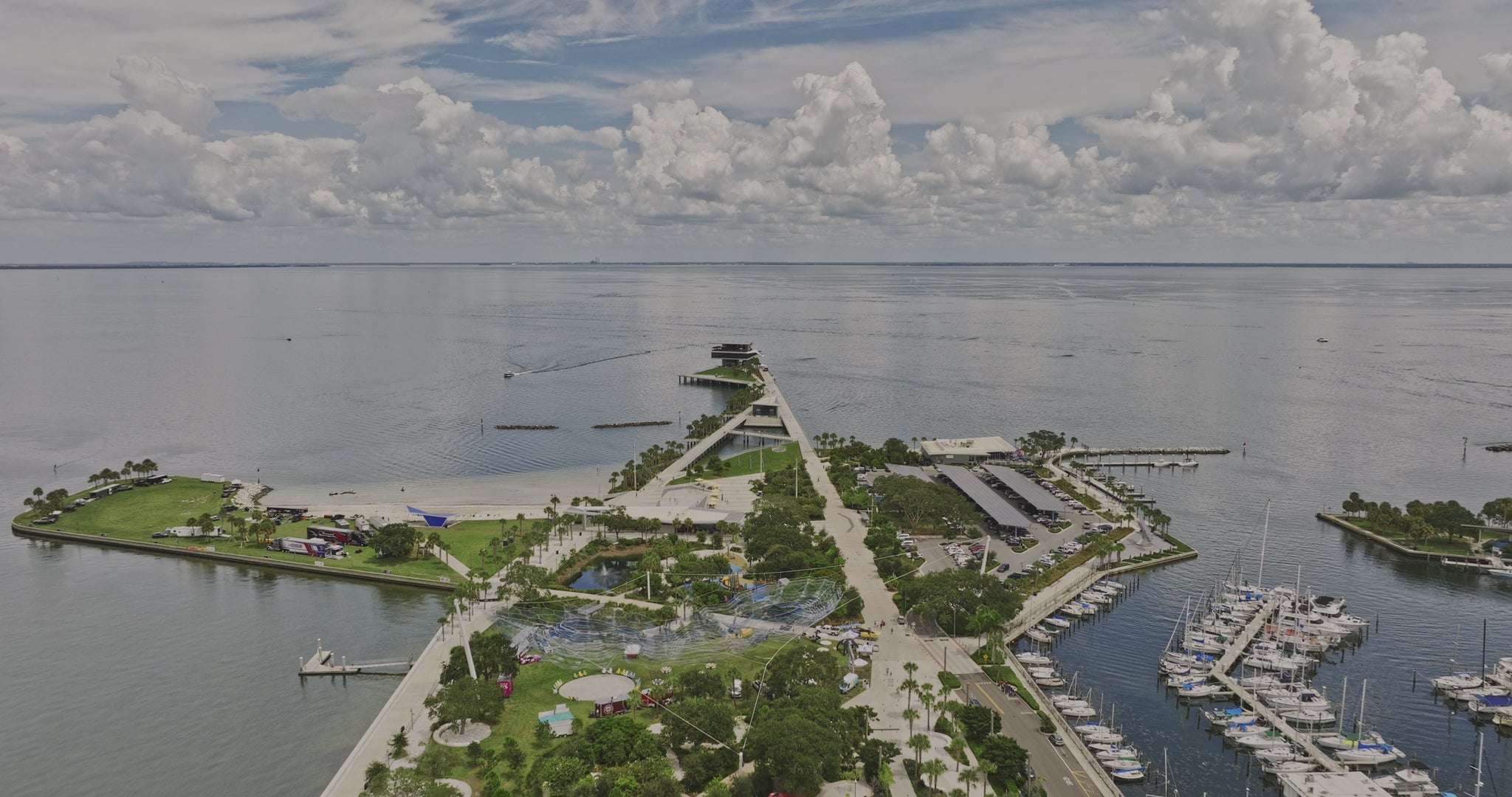 Aerial view of the St Petersburg waterfront park with pier, green spaces, and a marina on a partly cloudy day